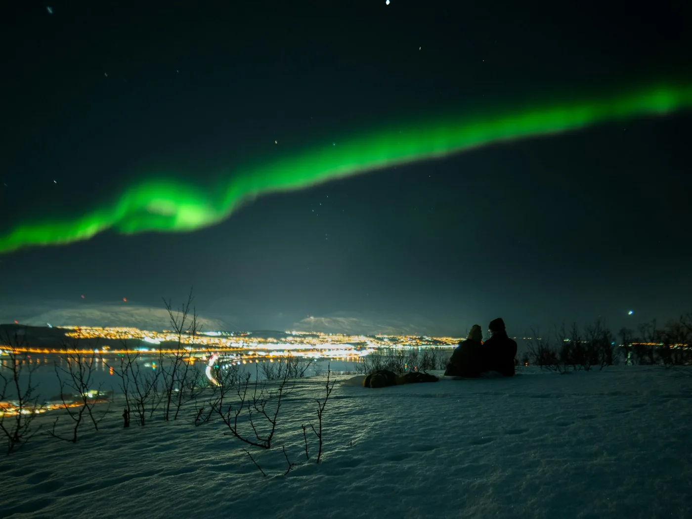 Světla Tromsø mezi zasněženými štíty v arktické zimě